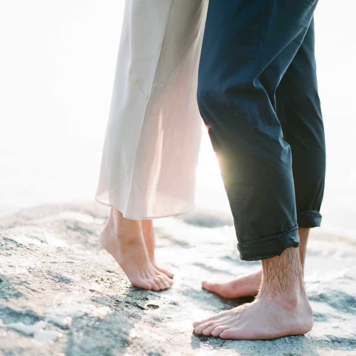 An empty nest couple reconnecting using couple rituals (their lower legs, showing they are in a hug on the beach)