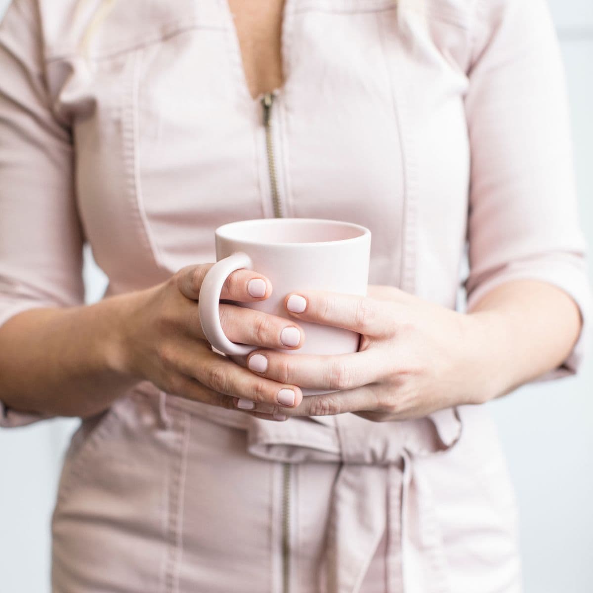 woman in a pink jumpsuit with a cup of coffee putting herself first in midlife