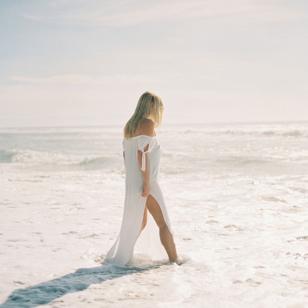 woman with her head down walking in the water
