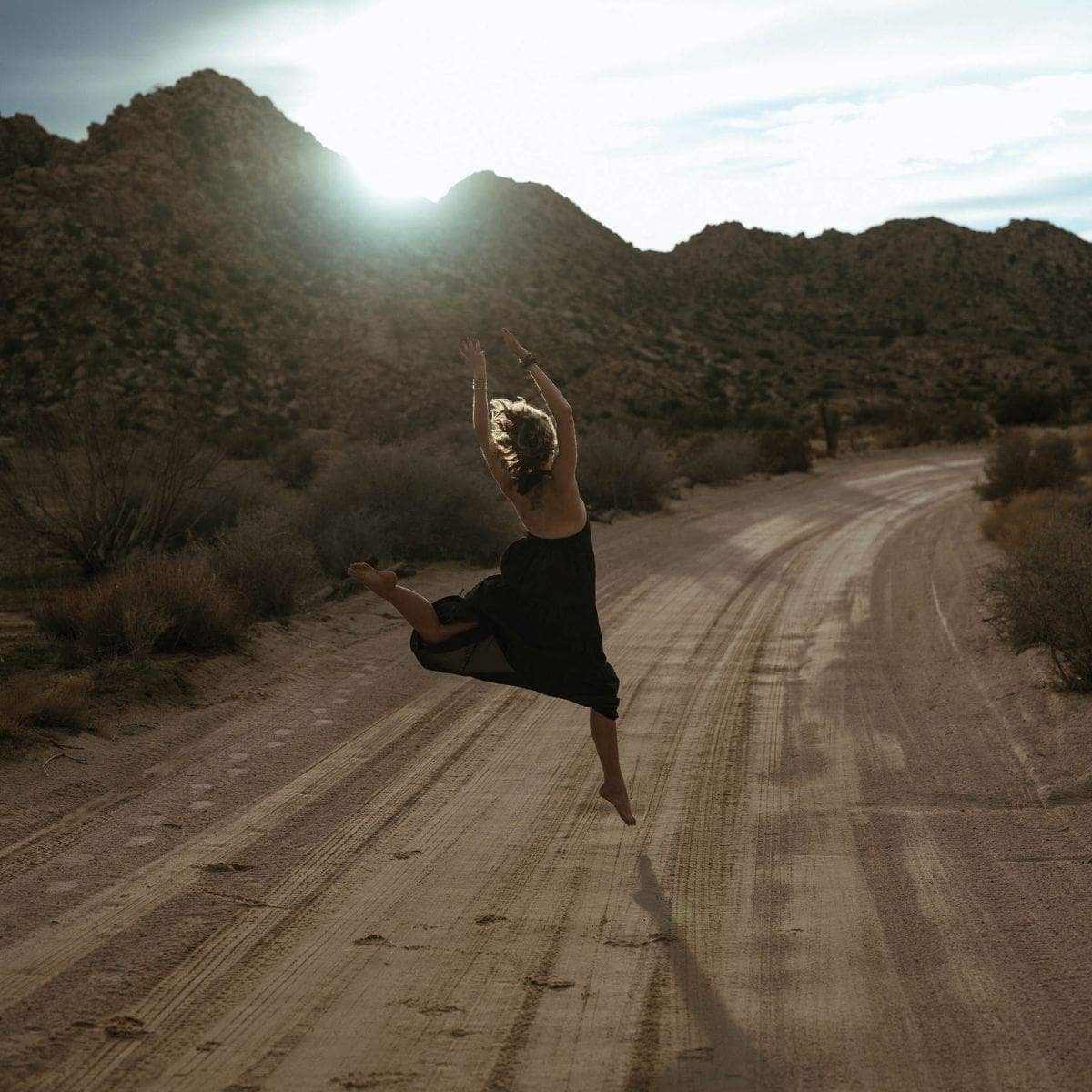 Woman leaping on a dirt road celebrating using her strengths to survive and thrive